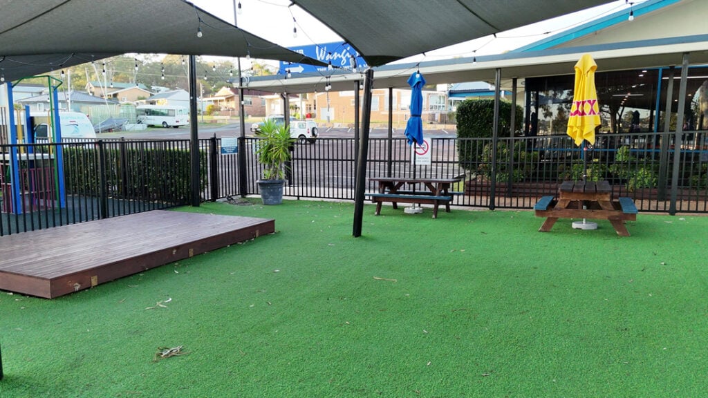 Outdoor seating area with umbrellas and small stage at Wangi RSL Club