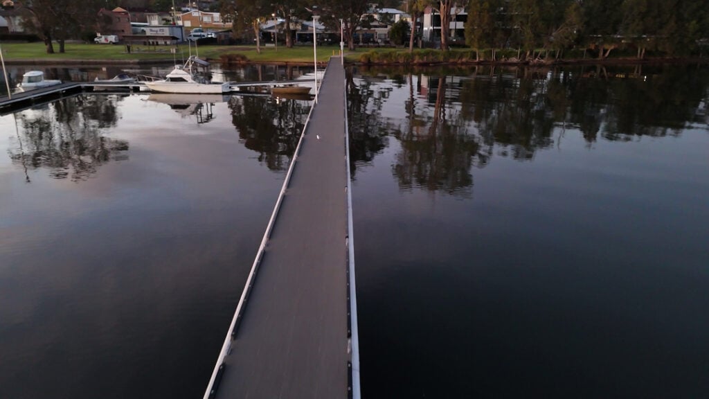 Walkway over the lake leading to Wangi RSL Club with boats moored nearby
